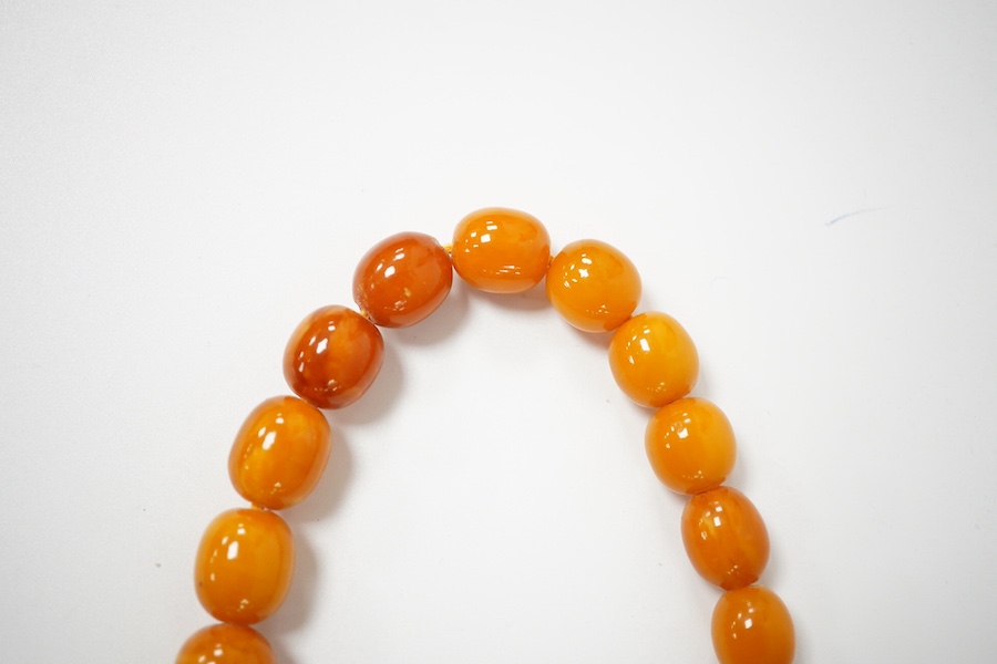 A single strand graduated amber bead necklace, 70cm, gross weight 67 grams, together with an amber bead bracelet, gross weight 20 grams. Condition - poor to fair